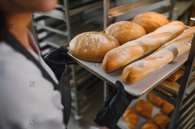 stock-photo-baker-wearing-black-gloves-holding-metal-tray-with-freshly-baked-loaves-of-bread-and-baguettes-in-2705778695(1).jpg